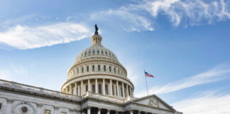 The U.S. Capitol building with a dome and American flag against a blue sky