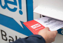 Mail Ballots Flagged—What Did USPS See? Person placing a mail-in ballot into a voting drop box