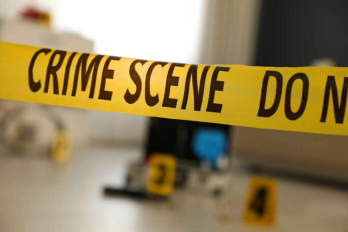 shutterstock_1925163116 Yellow crime scene tape with evidence markers in a room