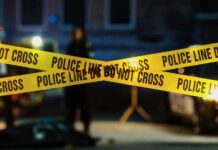 Trafficked Teen Identified — 26 Years Later Police tape marking a crime scene with blurred figures in the background