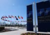 Russia’s ‘Target List’ Threat—Where’s The Proof? Flags of various nations displayed outside NATO headquarters under a clear blue sky