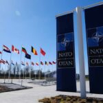 Russia’s ‘Target List’ Threat—Where’s The Proof? Flags of various nations displayed outside NATO headquarters under a clear blue sky
