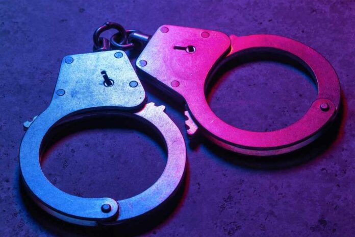 Closed,Handcuffs,On,A,Dark,Background,,Illuminated,With,Mixed,Red Close-up of metallic handcuffs illuminated with neon lights