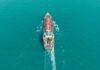 Aerial view of a cargo ship navigating through turquoise waters