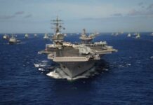 Trump Eyes Uranium Grab Inside Iran An aircraft carrier surrounded by various naval ships in the ocean