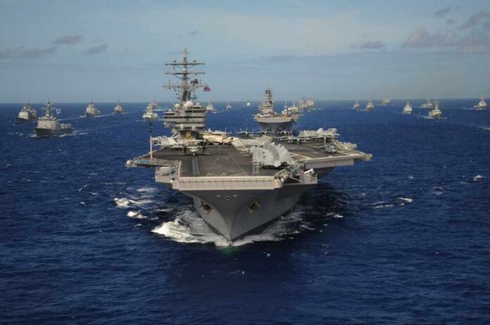 The,Nimitz-class,Aircraft,Carrier,Uss,Ronald,Reagan,Leads,A,Mass An aircraft carrier surrounded by various naval ships in the ocean