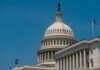 United States Capitol dome with American flags against a blue sky