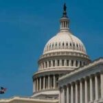 United States Capitol dome with American flags against a blue sky