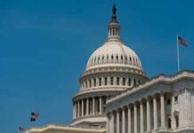 United States Capitol dome with American flags against a blue sky