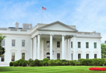 Security Wall Fight Erupts at Pennsylvania Ave The White House with an American flag flying above, surrounded by greenery