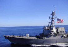 A naval destroyer sailing in the ocean with an American flag