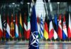 NATO flag with member country flags in the background