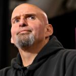 Bipartisan Cash Pipeline Sparks Outrage bald man with goatee speaking at a microphone