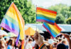 Church Pride Sponsor Ignites Doctrinal Meltdown A hand holding rainbow flags at a pride event with a crowd in the background