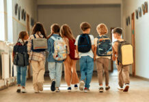 Billion-Dollar Foster Fix — Where’s The Proof? A group of children walking together in a school hallway, each carrying a backpack