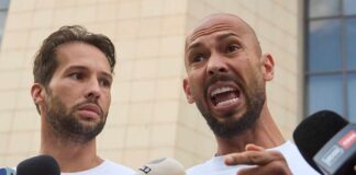 Two men speak into microphones during an outdoor press conference