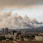 Toxic Haze Slams 100 Million City skyline with smoke clouds from a wildfire in the background