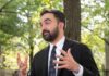 Man in a suit gesturing while speaking outdoors