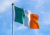 Irish flag on a flagpole against a blue sky