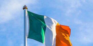 Irish flag on a flagpole against a blue sky