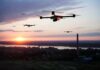 Drones flying over a river landscape at sunset