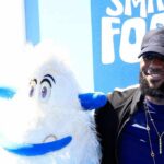 man posing with a white yeti mascot