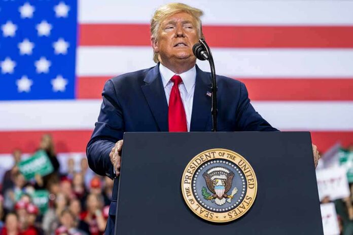 person speaking at a podium with U.S. flag backdrop