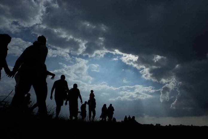 Silhouettes of people walking under dramatic cloudy sky