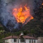 Toxic Smoke Traps Thousands Near Valencia Wildfire burning on a hillside near homes