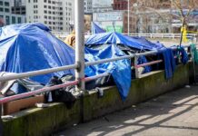 Tents covered with blue tarps along a city sidewalk
