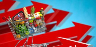 Shopping cart full of groceries on red upward arrows labeled inflation