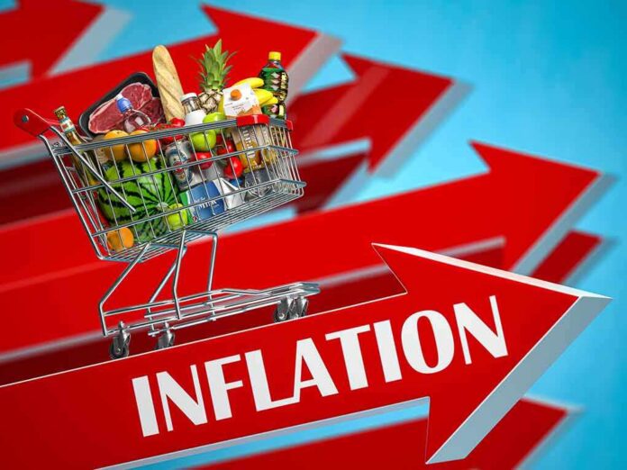 shutterstock_1976190356 Shopping cart full of groceries on red upward arrows labeled inflation