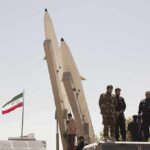 Iran Victory Boast — Trump Punches Back soldiers stand beside large missiles at outdoor display