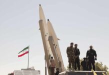 Iran Victory Boast — Trump Punches Back soldiers stand beside large missiles at outdoor display