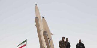 soldiers stand beside large missiles at outdoor display