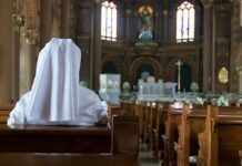 Trans Activist Roils John Paul II’s Diocese Person in white habit seated in a church pew facing the altar