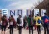 Group of people holding signs spelling ENOUGH at a street protest