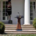 Blanche Slams AI Rulemaking Push Podium with presidential seal in a garden colonnade