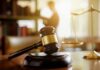 Judge's gavel on a desk with scales of justice in background