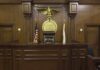 Interior of a courtroom featuring a judges bench and American flag