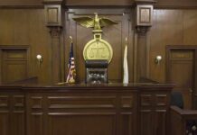 Courtroom Shock: ‘Woman’ Redefined Statewide Interior of a courtroom featuring a judges bench and American flag