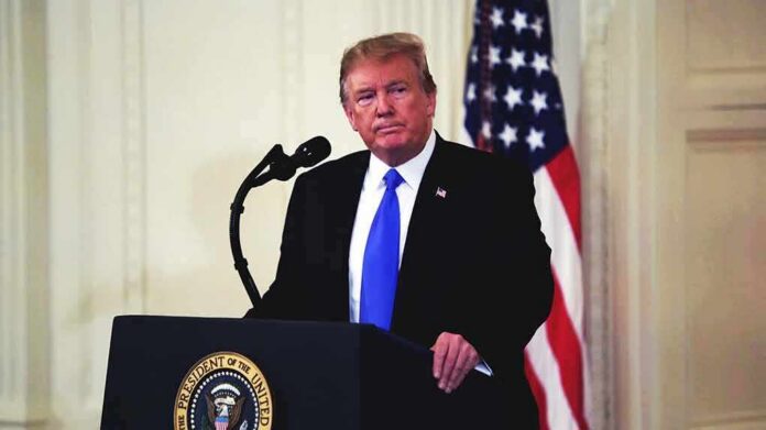 man at podium with microphone and US flag