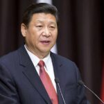 Power Play: Xi Steps Into Iran Standoff Xi Jinping speaking at a podium with microphones