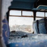 Bus interior with shattered windows and blue patterned seats