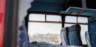 Bus interior with shattered windows and blue patterned seats