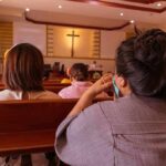 Christian Nationalism Storm: Pastor Defies Critics people seated in church pews facing a cross