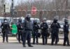 Group of police officers in riot gear standing on a street; Brian Folkerts present