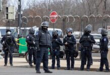 Major Incident Erupts Outside RAF Fairford Group of police officers in riot gear standing on a street; Brian Folkerts present
