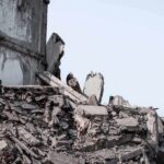 Collapsed concrete building rubble under a clear sky