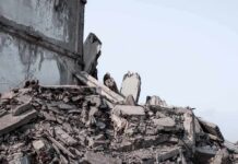 Collapsed concrete building rubble under a clear sky